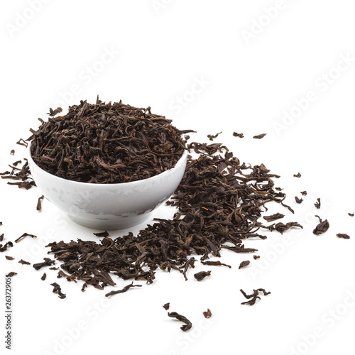 Dried tea leaves in ceramic cup over white background.