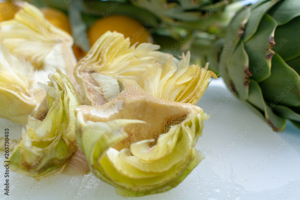 Preparation of heads of fresh raw artichokes plants from artichoke plantation in Argolida, Greece ready to cook with lemon Preparation of heads of fresh raw artichokes plants from artichoke plantation in Argolida, Greece ready to cook with lemon