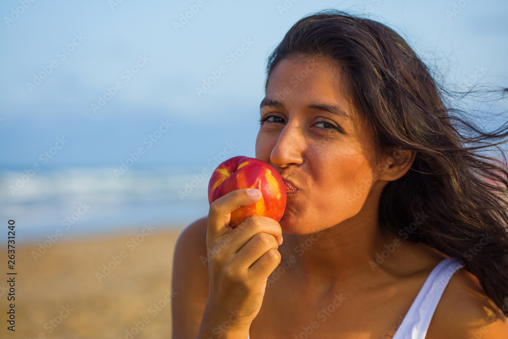 Young indian woman eating fruit on the beach Young indian woman eating fruit on the beach