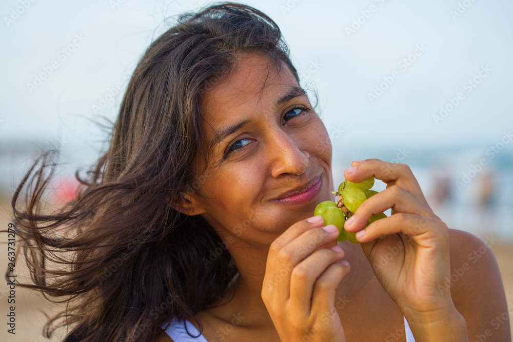 young Indian woman eating fruit on the beach young Indian woman eating fruit on the beach