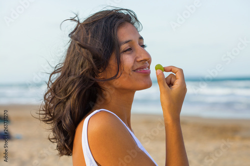 young woman eating fruit on the beach