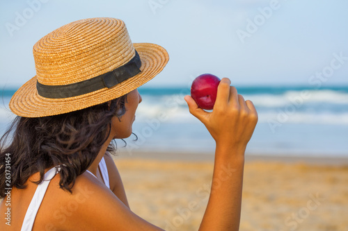 young woman eating fruit on the beach