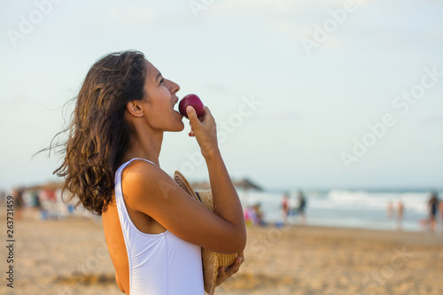 Young indian woman eating fruit on the beach