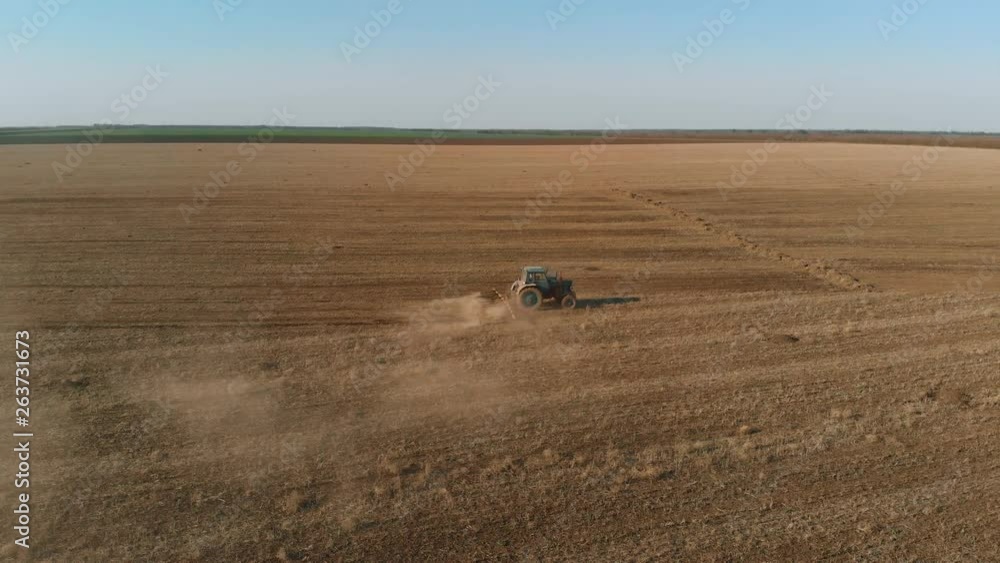 Blue tractor with towed harrow handles ground in autumn after harvest. Agronomic activities in spring Blue tractor with towed harrow handles ground in autumn after harvest. Agronomic activities in spring
