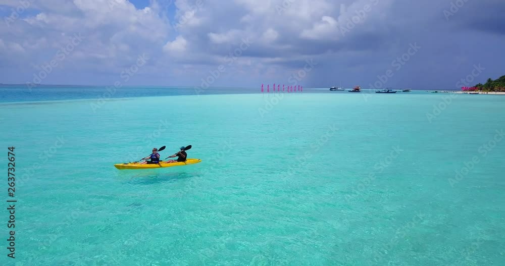 Two men paddle in sync across the frame as the camera pulls away to reveal the open ocean beyond an island coast in the Maldives. Red marker flags and boats on the horizon. Aerial, pullaway, 4k. Two men paddle in sync across the frame as the camera pulls away to reveal the open ocean beyond an island coast in the Maldives. Red marker flags and boats on the horizon. Aerial, pullaway, 4k.
