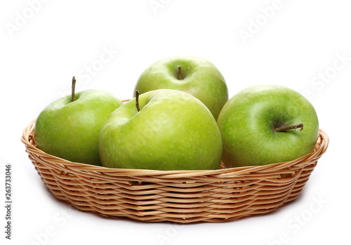 Tableau sur toile Green apple in wooden wicker basket isolated on white background