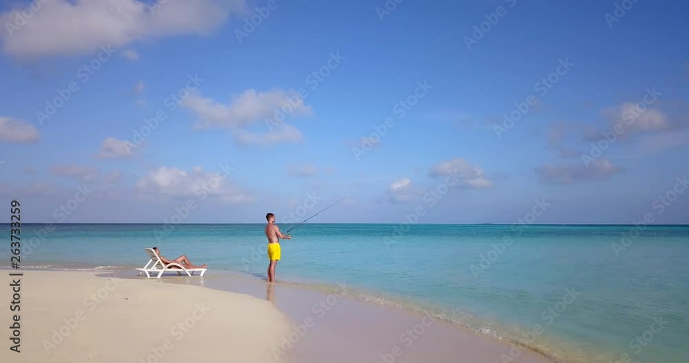 Tropical getaway, woman sunbaths and watches man fishing on perfect sandy beach 4k Tropical getaway, woman sunbaths and watches man fishing on perfect sandy beach 4k