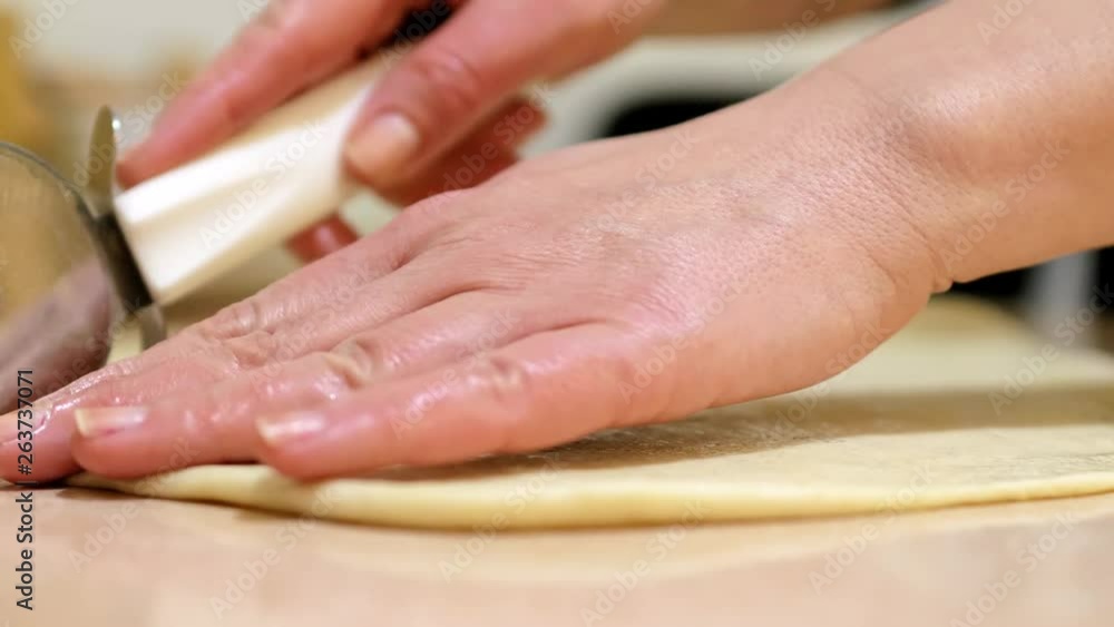 Woman using rolling pin to roll out dough for homemade dinner rolls; cut dough; slow motion; 4K. Woman using rolling pin to roll out dough for homemade dinner rolls; cut dough; slow motion; 4K.