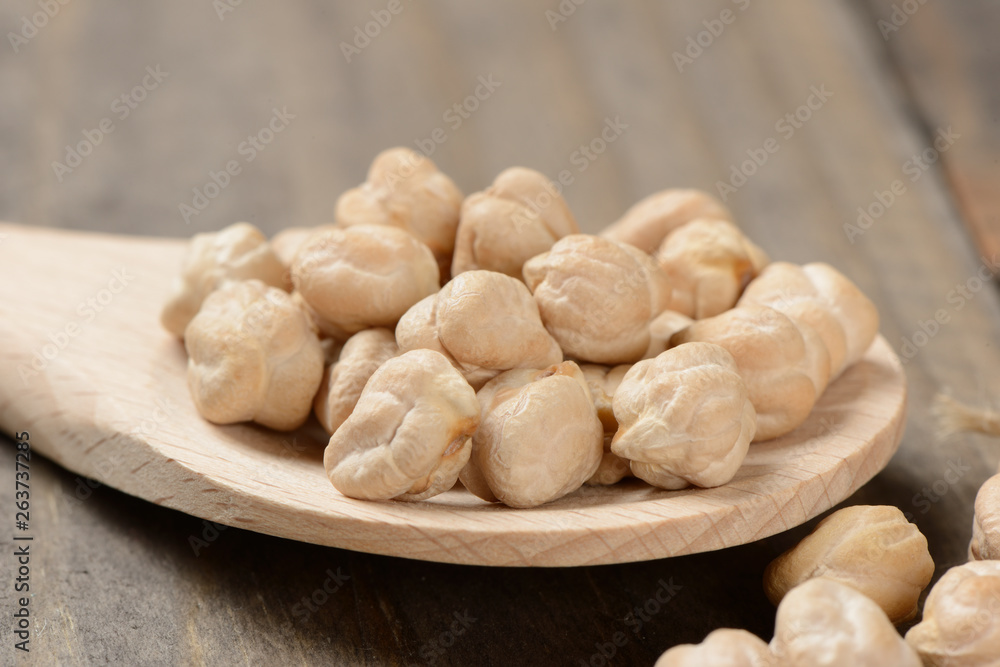 Garbanzos gordos en una cuchara de madera sobre fondo de madera, detalle Garbanzos gordos en una cuchara de madera sobre fondo de madera, detalle