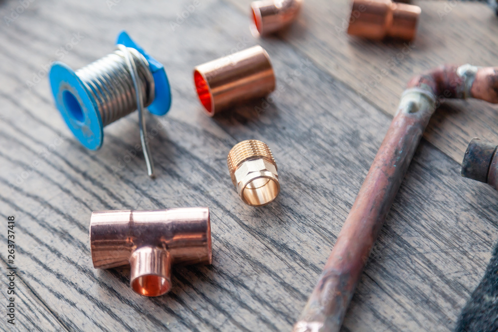 Close-up soldering, plumbing, construction professional tools, parts of copper pipes on a wooden background. Concept of professional repair of water supply, replacement old pipes with new ones