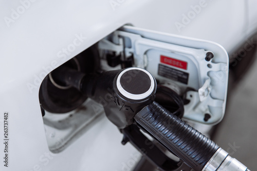 young pretty woman at gas station filling up car tank