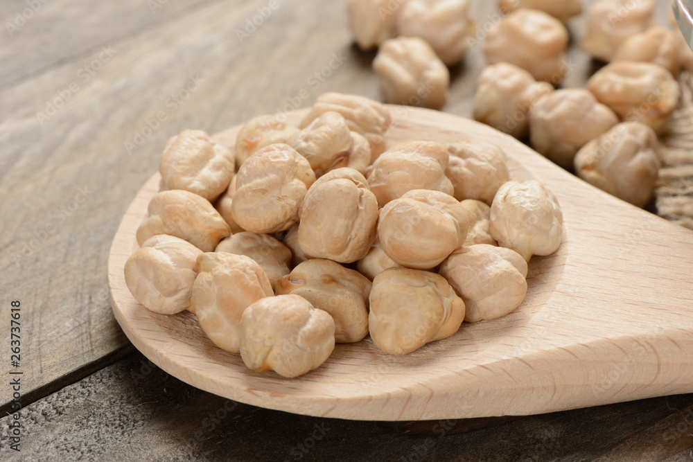 Garbanzos gordos en una cuchara de madera sobre fondo de madera, detalle Garbanzos gordos en una cuchara de madera sobre fondo de madera, detalle