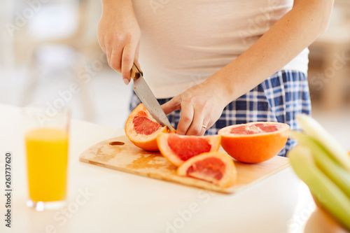Close up of unrecognizable woman cutting oranges for healthy breakfast in morning  copy space