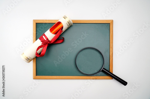 Scroll of certificate, magnifying glass and the black board with copy space , A Flat lay