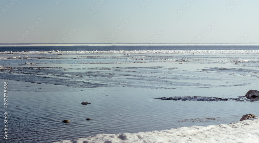 Obraz premium Snow pile, hill. Large snow drift isolated on a blue sky background, outdoor view of ice blocks at frozen finland lake in winter