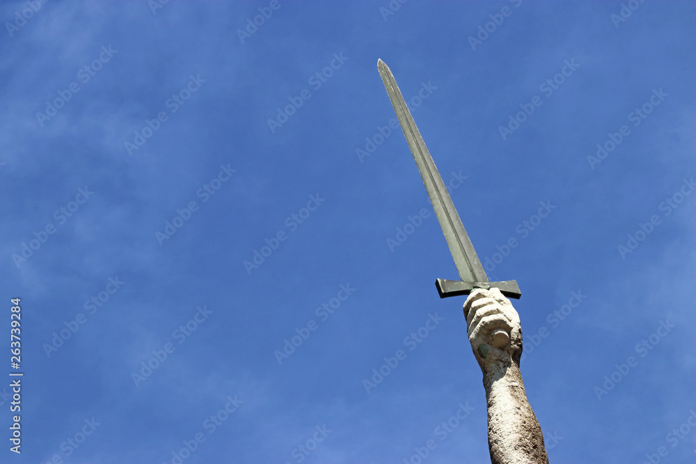 Fototapeta premium stone arm holding a sword up in the air