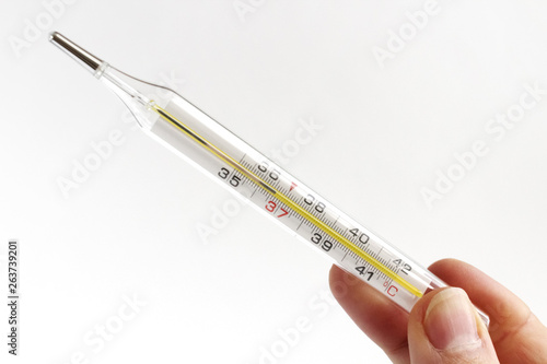 Hand with glass mercury thermometer with celsius degree. Thermometer close-up on white background. Health temperature concept.