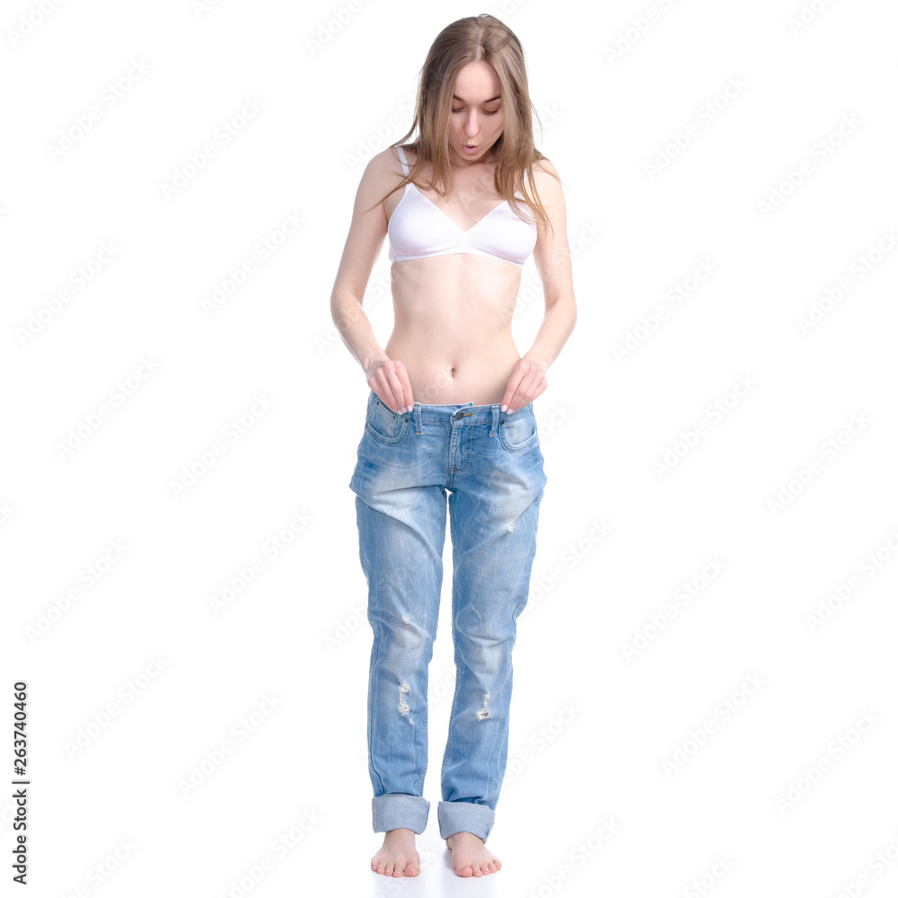 Beautiful woman in big jeans weight loss slimming on a white background. Isolation Beautiful woman in big jeans weight loss slimming on a white background. Isolation