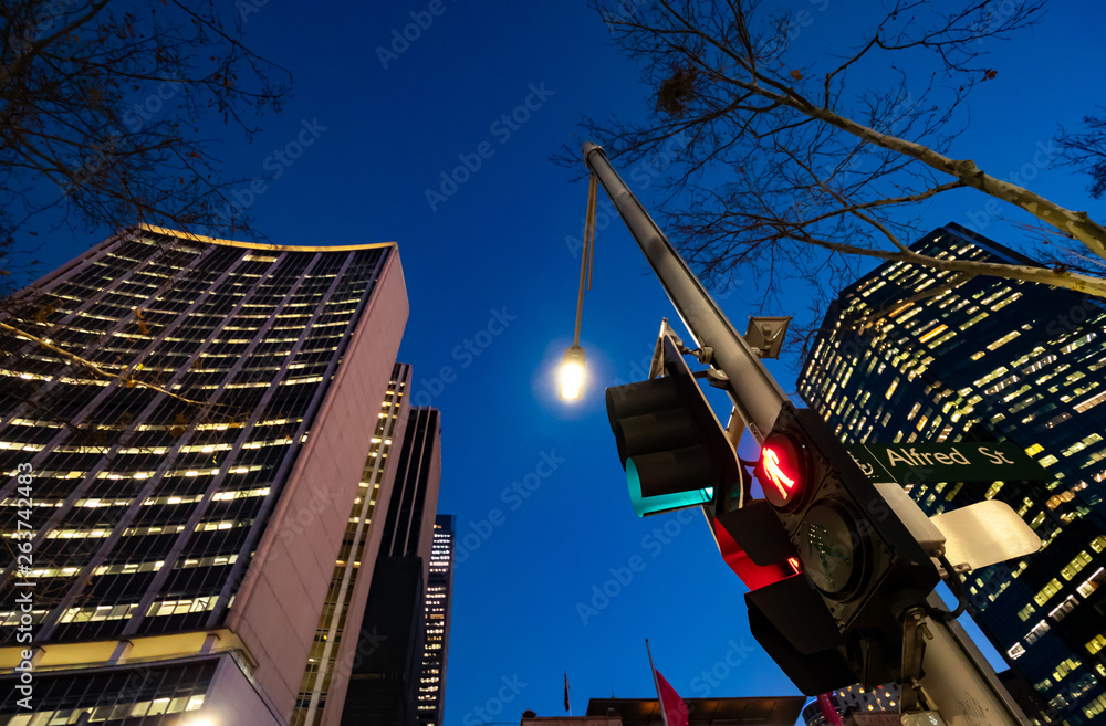 Red pedestrian traffic lights with high office buildings in the background at night Red pedestrian traffic lights with high office buildings in the background at night