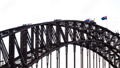 People walking on the Sydney Harbour Bridge with waving Australian flags