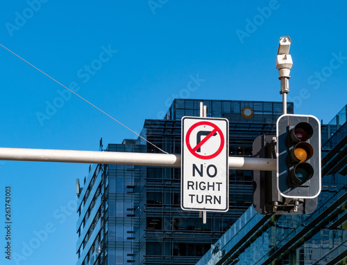 Traffic lights on yellow and no right turn with a business building in the background