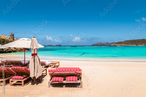 Fototapeta Naklejka Na Ścianę i Meble -  Beach chairs and umbrella on tropical beach. Summer vacation and relaxation background.