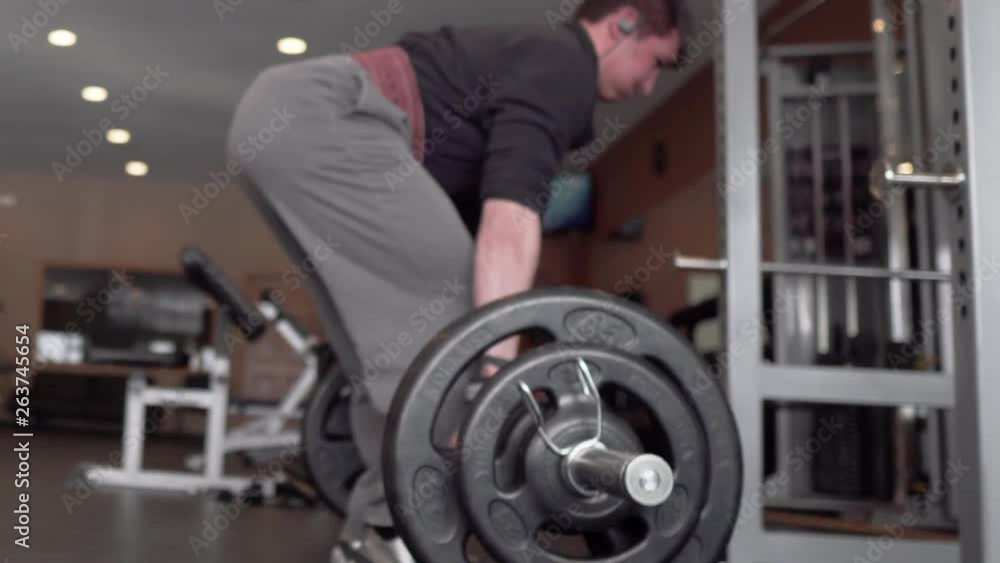 Person exercising and lifting weights in the gym. Slow pan to the left. 24 fps. Shallow depth of field. Person exercising and lifting weights in the gym. Slow pan to the left. 24 fps. Shallow depth of field.