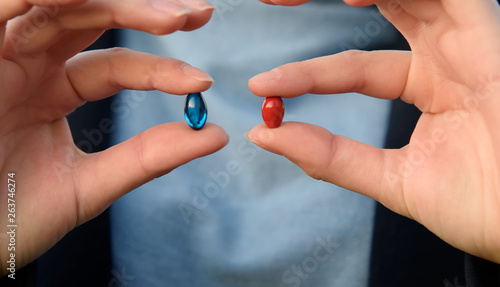 Female hands are holding blue and red pills. Blue and red. Concept: make your choice.