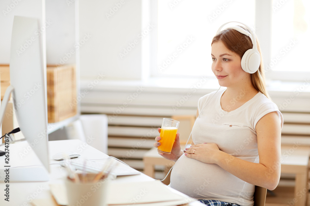 Portrait of pregnant woman drinking orange juice watching health videos at home, copy space, copy space