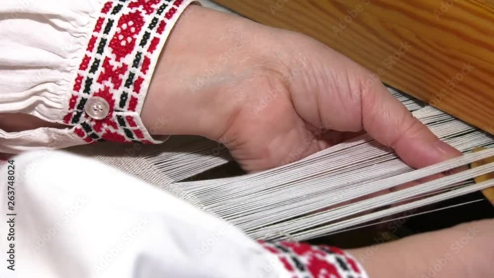 A traditional hand-weaving loom being used to make cloth.  Hands of a man who weaves on a loom