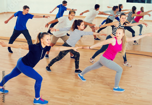 vigorous teenage boys and girls learning in dance hall