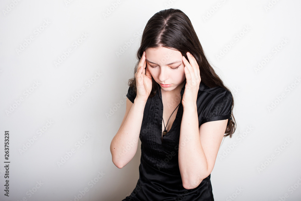 young woman is suffering from a headache. Portrait of a girl clutching her head. Migraines and blood pressure problems young woman is suffering from a headache. Portrait of a girl clutching her head. Migraines and blood pressure problems