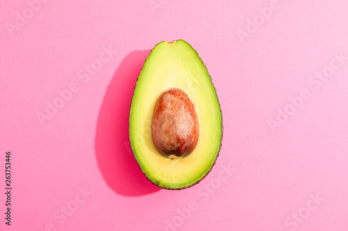 Rip cut avocado on pink background, space for text