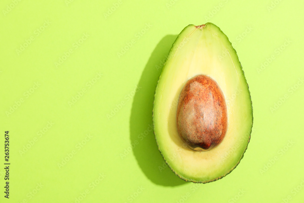 Rip cut avocado with space for text on green background, closeup
