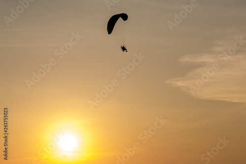 Silhouette of Paramotors flying to sky on sunset Adventure man active extreme sport pilot flying in sky with paramotor engine glider parachute. Paramotor flying on the sky at sunset.  © kanpisut