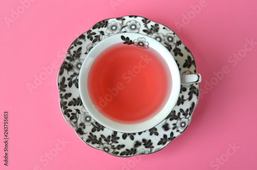Fruit tea in a fine black and white floral porcelain cup on vivid pink background with copy space