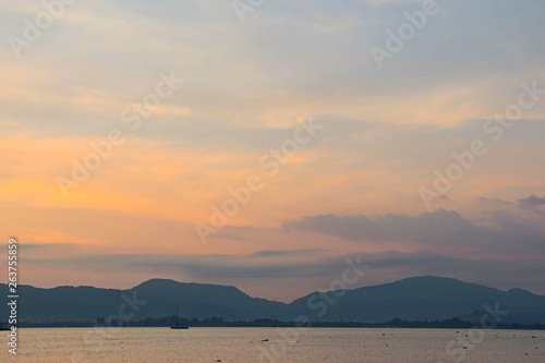 Sunset and dawn at sea against a backdrop of mountains and boats