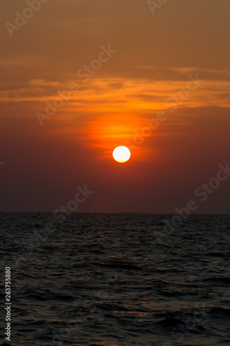 Fototapeta Naklejka Na Ścianę i Meble -  Bright sunset with large yellow sun under the sea surface. sunrise in the sea. Beautiful sunset above the sea. Tropical sunset on the beach.
