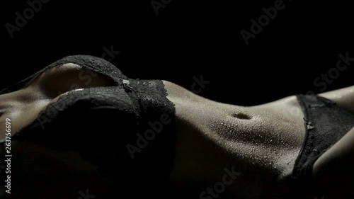 Close-up of a sexy woman's body lying down in black lace lingerie as her hips are writhing around