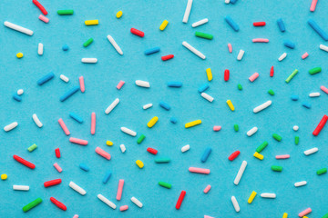 colorful sprinkles over blue background, decoration for cake and bakery
