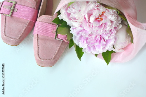 Suede leather ballerina flats shoes wrapped in gift tissue paper  with pink peonies bouquet and copy space photo