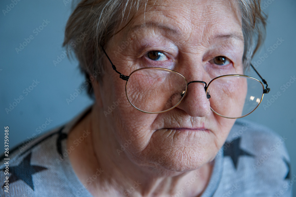 Beautiful elderly woman with gray hair in red glasses with wrinkled face. Retired waiting for guests. Social assistance, care for sick and elderly Beautiful elderly woman with gray hair in red glasses with wrinkled face. Retired waiting for guests. Social assistance, care for sick and elderly