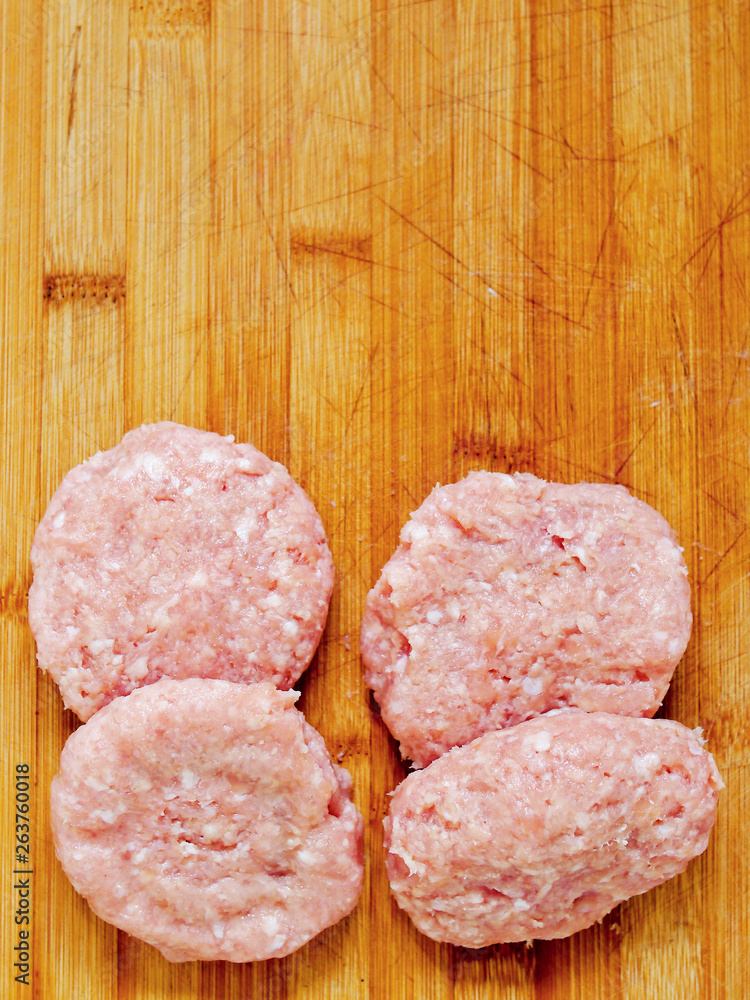 Fresh uncooked turkey burgers on a wooden board, Copy paste.