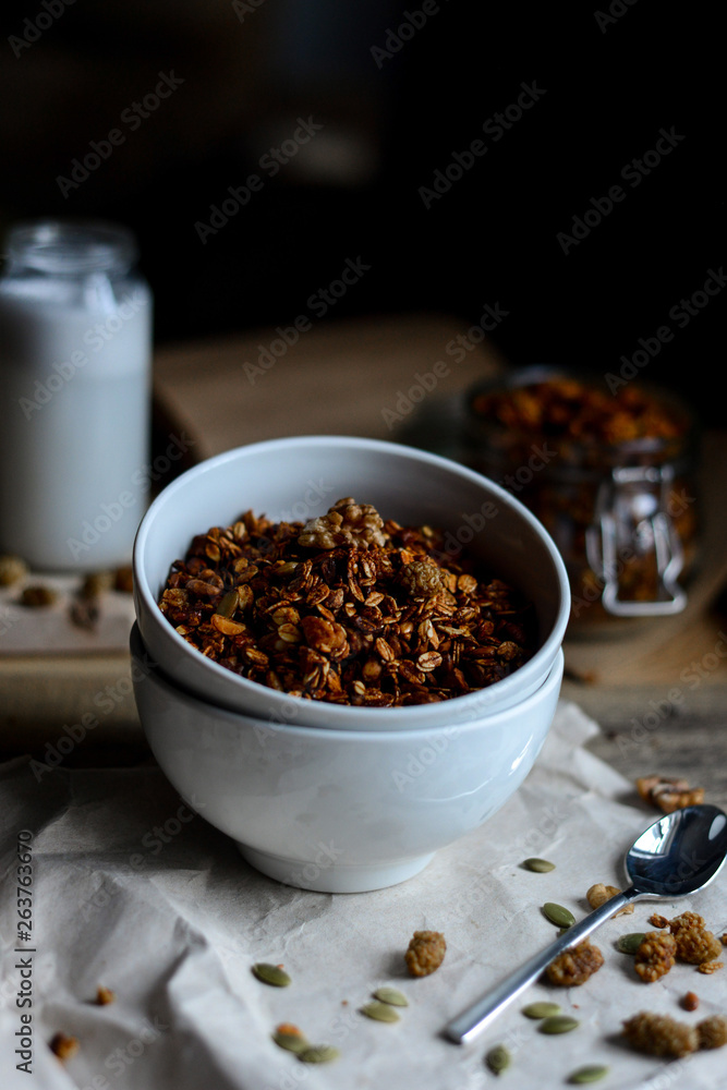 tasty homemade oats granola with nuts and berries in white ceramic bowl served with coconut milk on the wood table for breakfast early in the morning tasty homemade oats granola with nuts and berries in white ceramic bowl served with coconut milk on the wood table for breakfast early in the morning