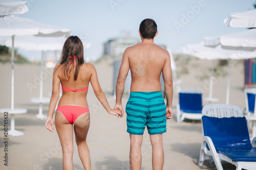 Back couple walking on the beach. On the back of a man and on the woman's buttocks is handprint of sand