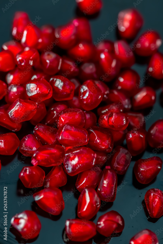 Beautiful blurry backdrop with red seeds pomegranate on a dark plate. Macro image of red grains. Soft focus. Copy space. Healthy concept. Beautiful blurry backdrop with red seeds pomegranate on a dark plate. Macro image of red grains. Soft focus. Copy space. Healthy concept.