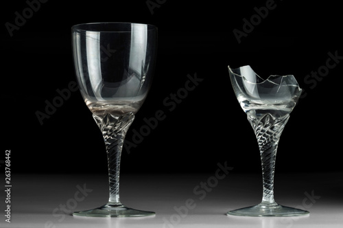 Two crystal wine glass on a black mirror background. New and broken.