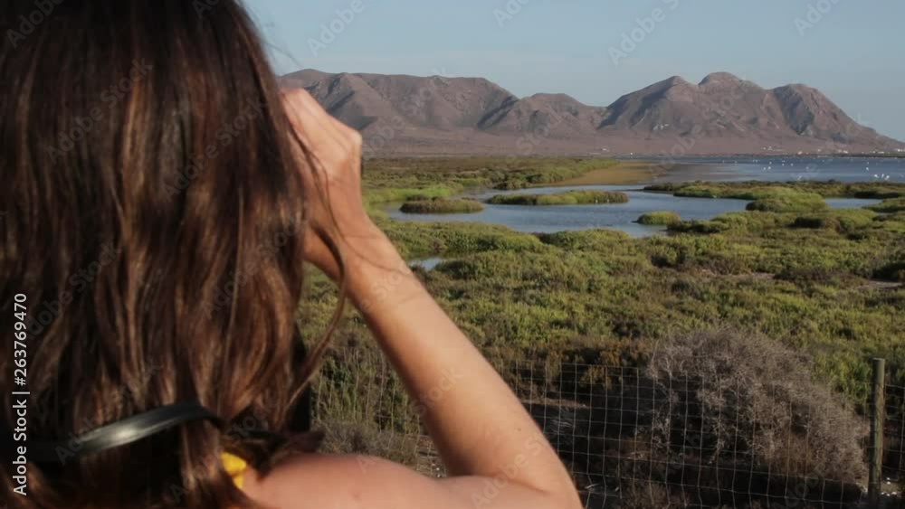 Close up young caucasian female looking though binoculars, nature reserve, Spain