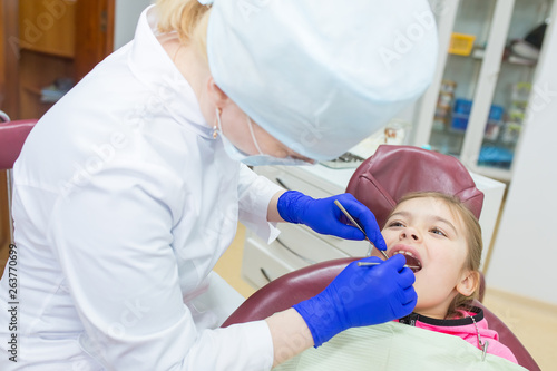 Little girl sits in a dental chair as a patient. Kid health care, dentistry, medicine concept. Doctor and patient