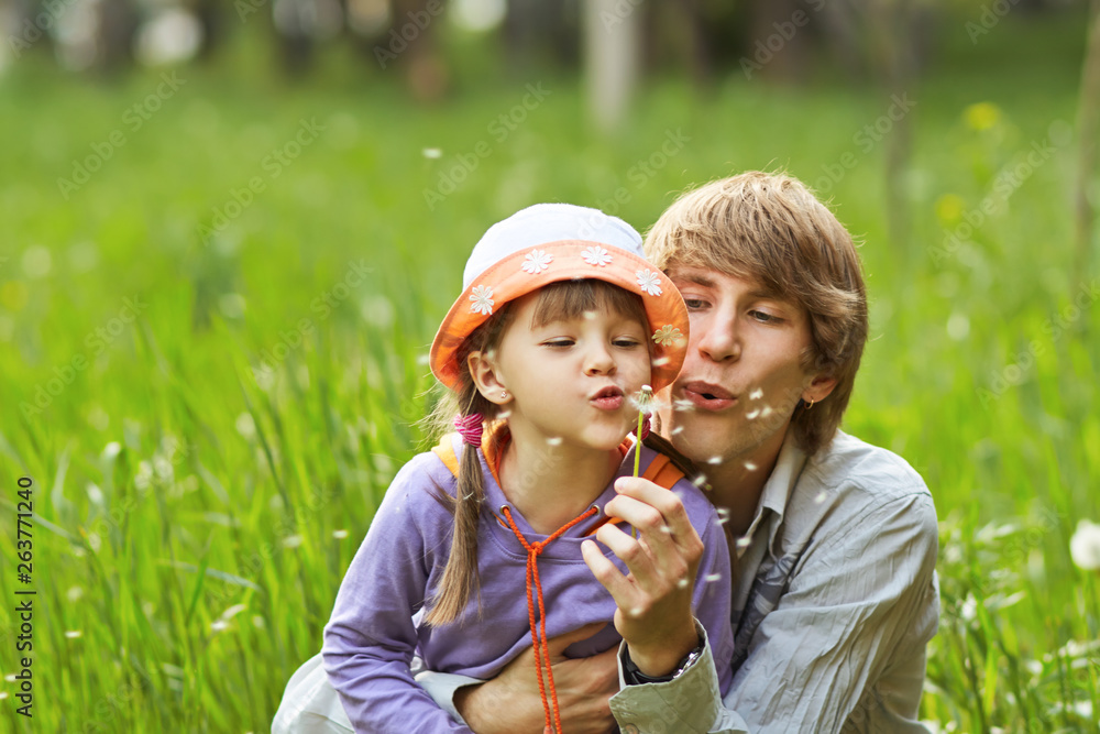 Fototapeta premium father and daughter blowing on dandelions in a summer